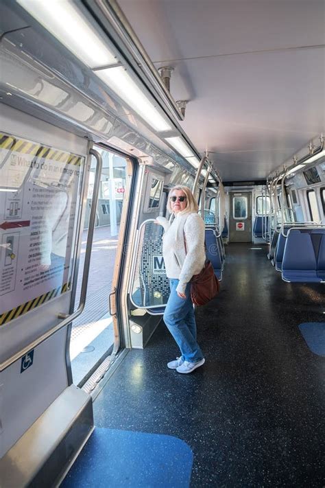 Blonde Adult Woman In An Empty Washington Subway Train Wearing Blue Jeans While Using Public