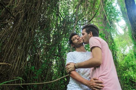 Una joven pareja de hombres gay besándose en el parque Foto Premium
