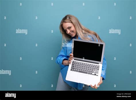 Happy Lucky Blonde Girl Demonstrates Laptop Screen Blank Space For Web Page On Blue Background