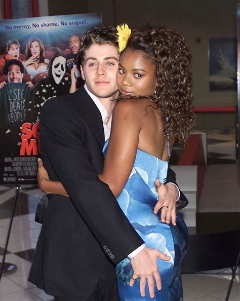 A Man And Woman Hugging Each Other In Front Of A Movie Poster At An Event