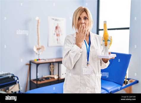 Femme blonde d âge moyen portant un modèle anatomique de l articulation du genou à la clinique