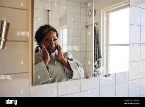 Mature Woman Touching Face While Looking In Mirror In Bathroom At Home Stock Photo Alamy