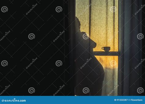 A Naked Girl Is Standing By The Window Behind The Curtain And Drinking Coffee At Dawn Stock