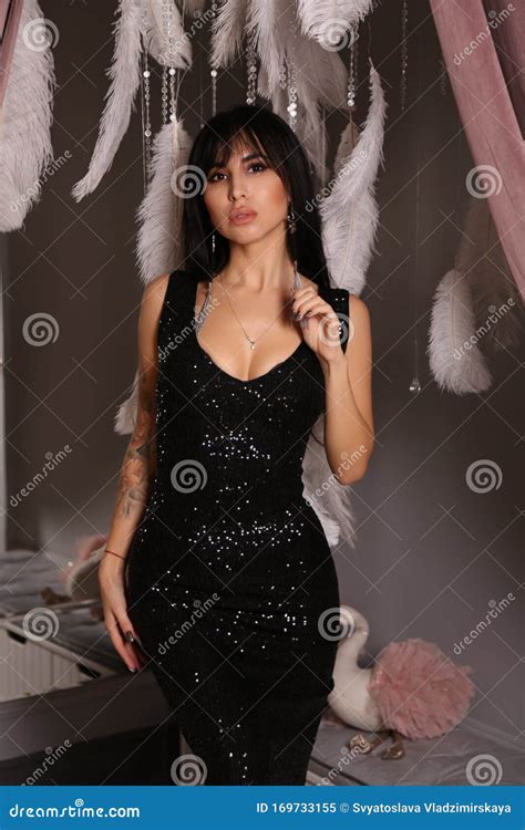 Woman With Dark Hair In Elegant Black Dress Posing With Decorations