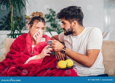 Man Taking Care Of His Sick Girlfriend Lying On The Sofa Stock Image