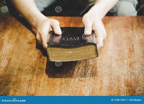 Hands Folded In Prayer On A Holy Bible In Church Concept For Faith