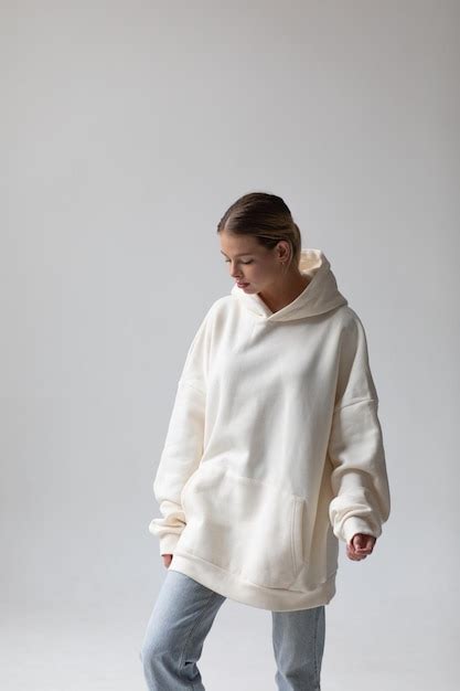 Une Belle Femme Blonde Dans Un Sweat à Capuche Blanc Et Un Jean Bleu Posant Sur Un Fond Blanc