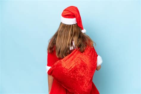 Jovem mulher caucasiana vestida de mamãe noel segurando saco de Natal