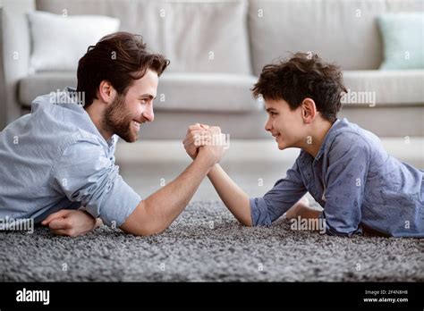 Happy Father Competing In Arm Wrestling With His Son Enjoying Time