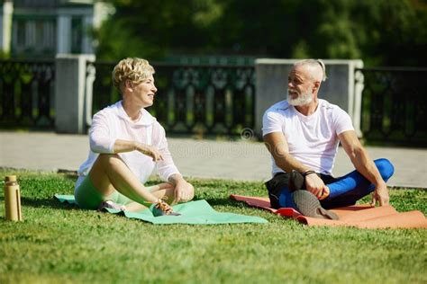 Early Morning Yoga Mature Couple Sportive Man And Woman Training Outdoors In Park On Warm