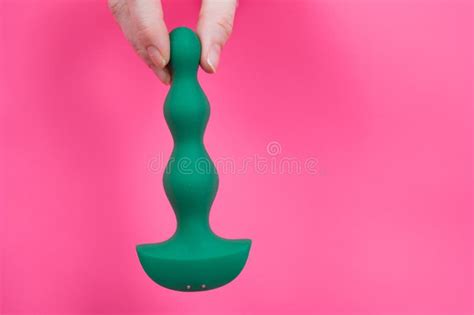 Female Hand Sticking Out With Green Anal Beads From Pink Paper Background Copy Space Stock