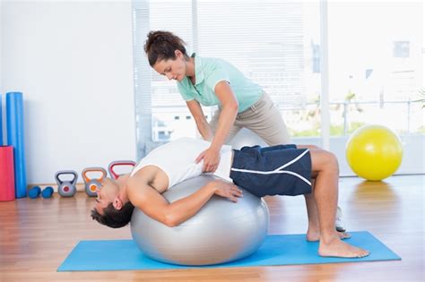 premium photo trainer helping man  exercise ball