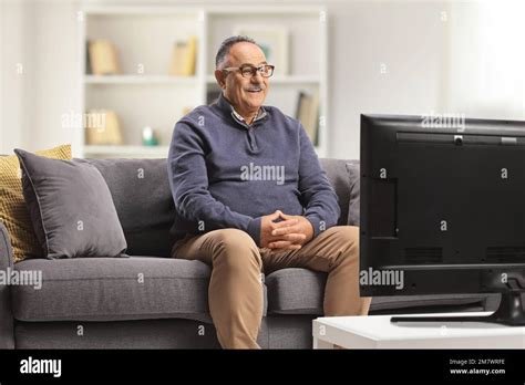 Happy Mature Man Sitting On A Sofa And Watching Tv At Home Stock Photo Alamy