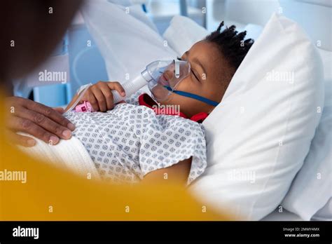 African american boy patient lying asleep in hospital bed wearing ...