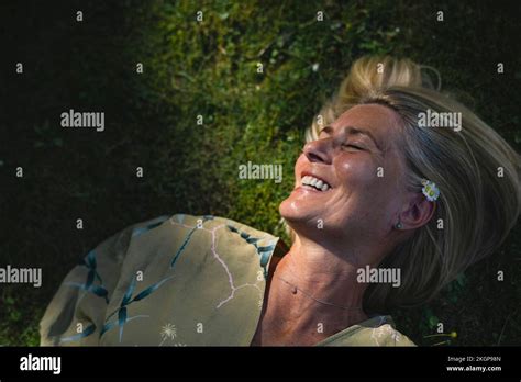 Happy Mature Woman Lying On Grass Enjoying Sunlight Stock Photo Alamy