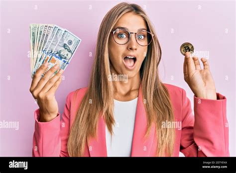 Jeune femme blonde portant le style d affaires tenant des dollars et bitcoin célébrant fou et