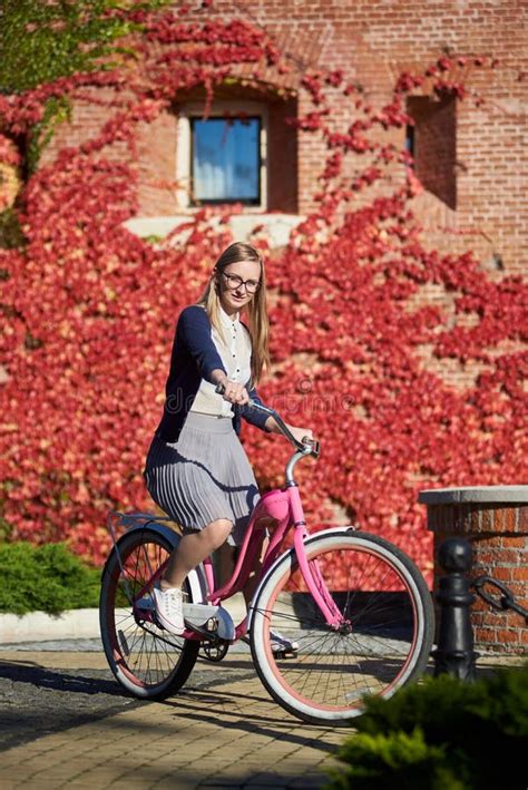 Fille Blonde Attirante La Bicyclette De Dame Rose Le Jour Ensoleill Sur Le Mur Envahi Avec Le