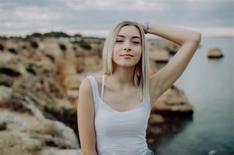 Portrait de jolie femme blonde posant sur une plage rocheuse avec un paysage de beauté Photo