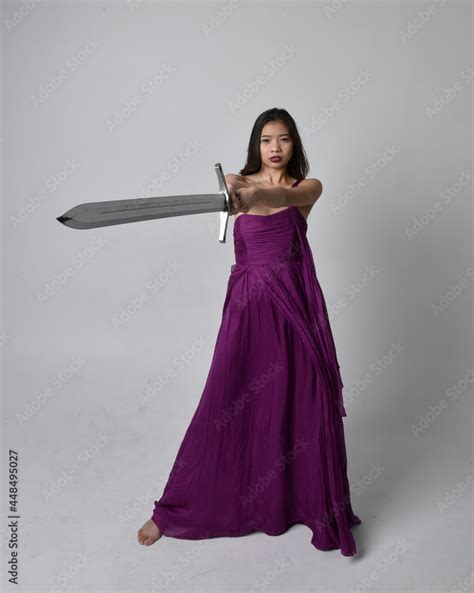 Full Length Portrait Of Pretty Brunette Asian Girl Wearing Purple Flowing Gown Sitting Pose