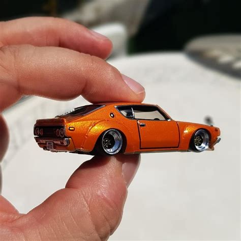 An Orange Toy Car Being Held In Someones Hand