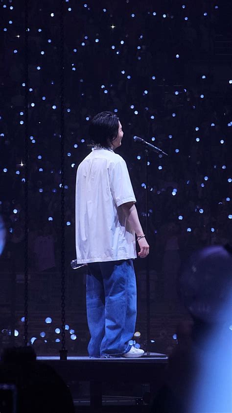 A Man Standing On Top Of A Stage With A Microphone In Front Of His Face