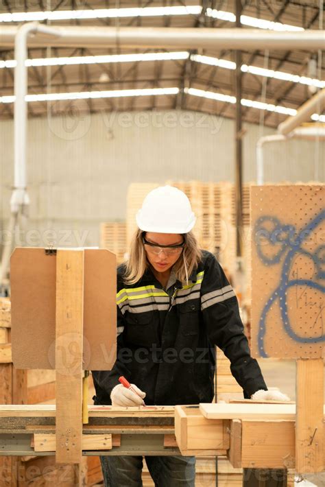Female carpenter working in a woodworking factory, She is wearing a