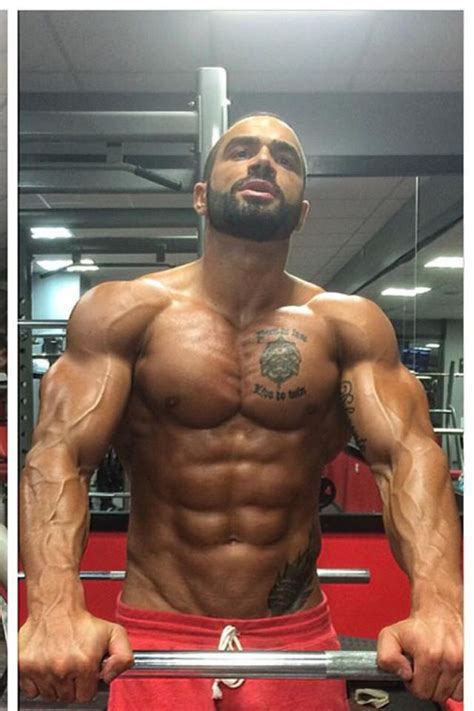 A Shirtless Man Is Posing In The Gym