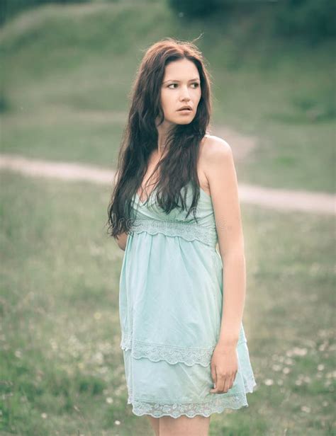 Thoughtful Young Woman With Long Hair Standing In A Meadow Stock Image