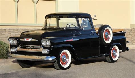 An Old Black Pickup Truck Parked In Front Of A Building