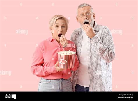 Shocked Mature Couple Eating Popcorn On Pink Background Stock Photo Alamy