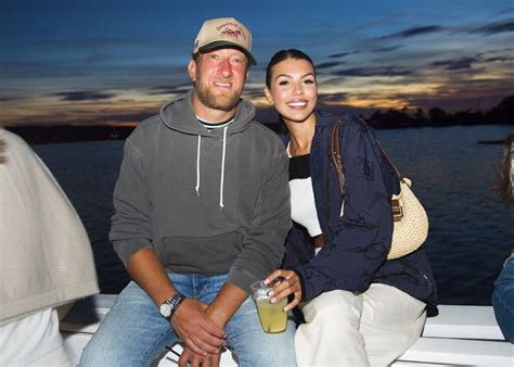 A Man And Woman Sitting On The Back Of A Boat At Dusk With Drinks In