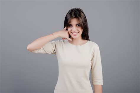 Premium Photo Beautiful Brunette Woman Showing Call Me Gesture Imitating Phone Isolated Over Grey