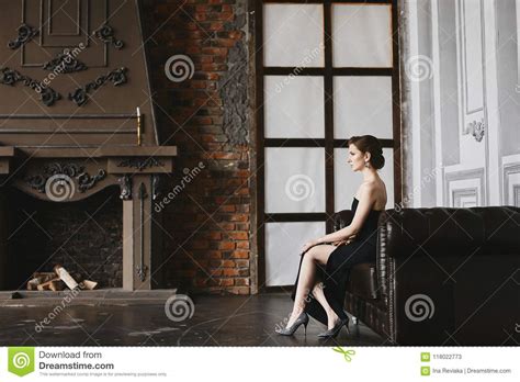 Fashionable And Beautiful Brunette Model Girl In Black Dress With A Cut To The Hip And Naked