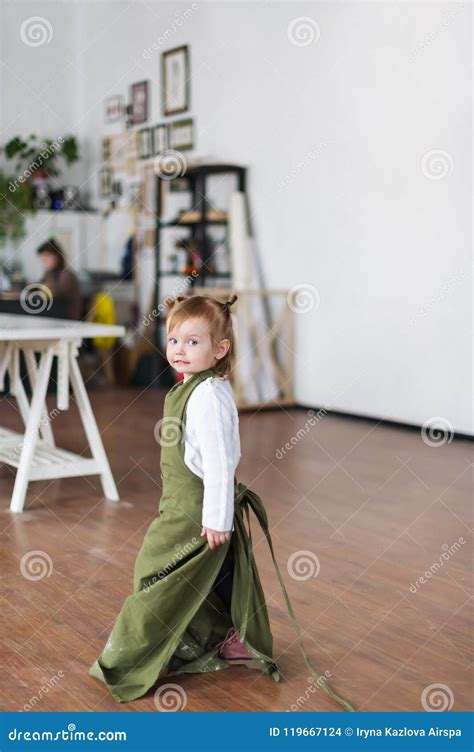 Cute Blonde Three Years Old Girl In White Jacket And Green Apron Is In A Creative Class Stock