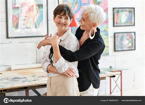 Cheerful Trendy Mature Woman Embracing Lesbian Partner Modern Art Workshop Stock Photo