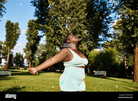 A Curvy African American Woman In A Blue Dress Standing Elegantly In A