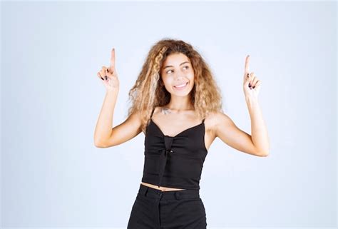 Femme Blonde Levant La Main Et Pointant Quelque Chose Au dessus Avec Des émotions Photo Gratuite