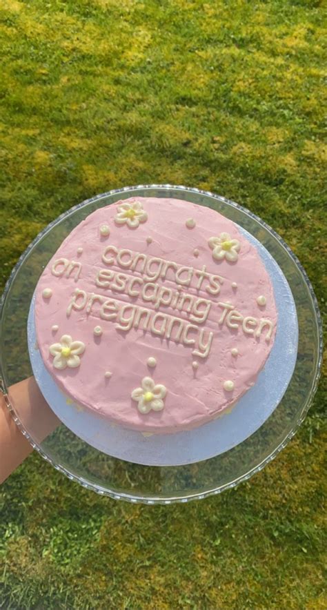 A Pink Frosted Birthday Cake Sitting On Top Of A Glass Plate In The Grass