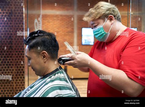 Profile Of A Fat Asian Barber With Mask Cutting The Hair Of A Gay Asian Man Stock Photo Alamy