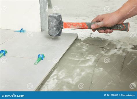 Worker With Rubber Hummer Installing Tiles Indoors Closeup Stock