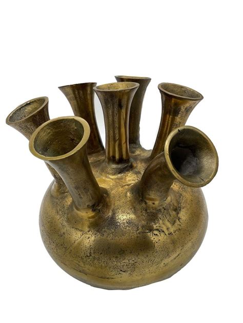 An Antique Brass Vase With Four Cups In The Center On A White