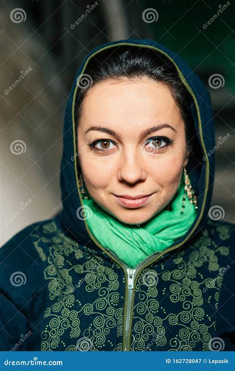 A Beautiful Woman Of Oriental Appearance With Make Up On Her Face In A Dark Hood To Look Forward