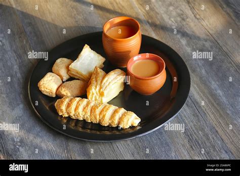Tabletop shot of tea cups with khari (salty puff pastry), cream roll ...