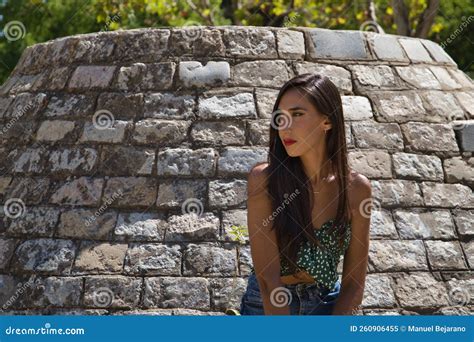 Jovem Morena Brunette Esbelta Vestida De Camisa Verde E Jeans Inclinada Contra Uma Parede De