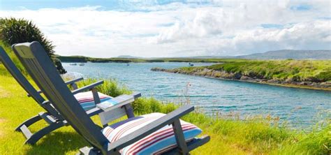 Two Lawn Chairs Sitting On The Side Of A River