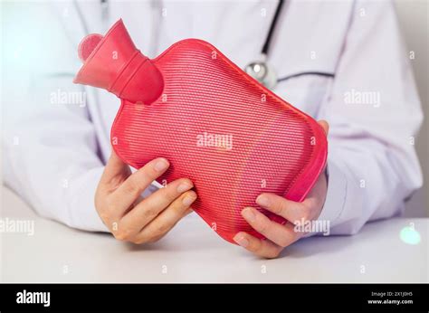 The Doctor Is Holding A Red Heating Pad With Hot Water In His Hands The Concept Of Heat