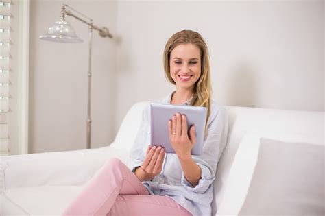 Premium Photo Smiling Casual Blonde Sitting On Couch Using Tablet