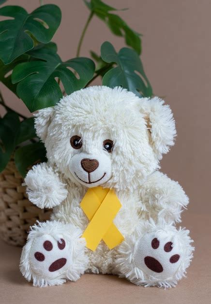 Premium Photo Toy Bear With A Yellow Ribbon On A Nude Background
