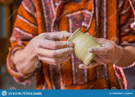 Professional Male Potter Examining Mug In Pottery Workshop Close Up