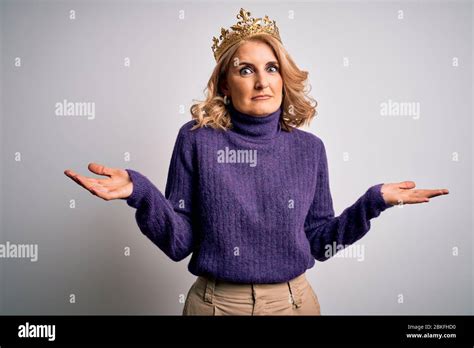 Middle Age Beautiful Blonde Woman Wearing Golden Crown Of King Over White Background Clueless